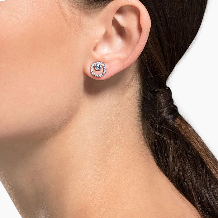 Close-up of a model wearing the Swarovski Creativity Circle Rose Stud Earring, the rose gold-plated and crystal-embellished piece complementing the ear with its sparkling design, suitable for elegant occasions.