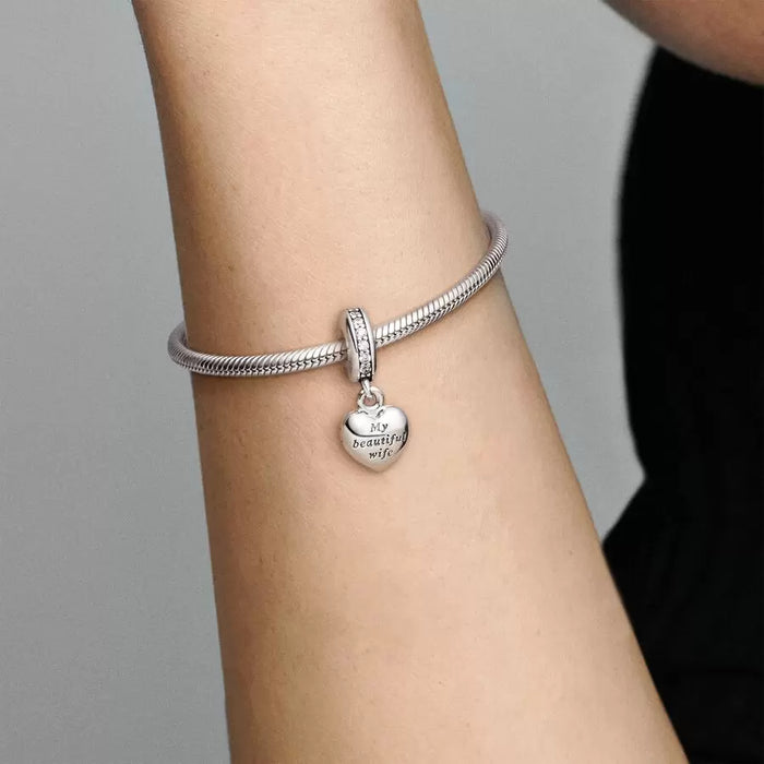 Pandora open heart-shaped sterling silver locket charm displayed on a plain silver bracelet worn by a model. The words "my beautiful wife" can be read at the center of the heart charm.